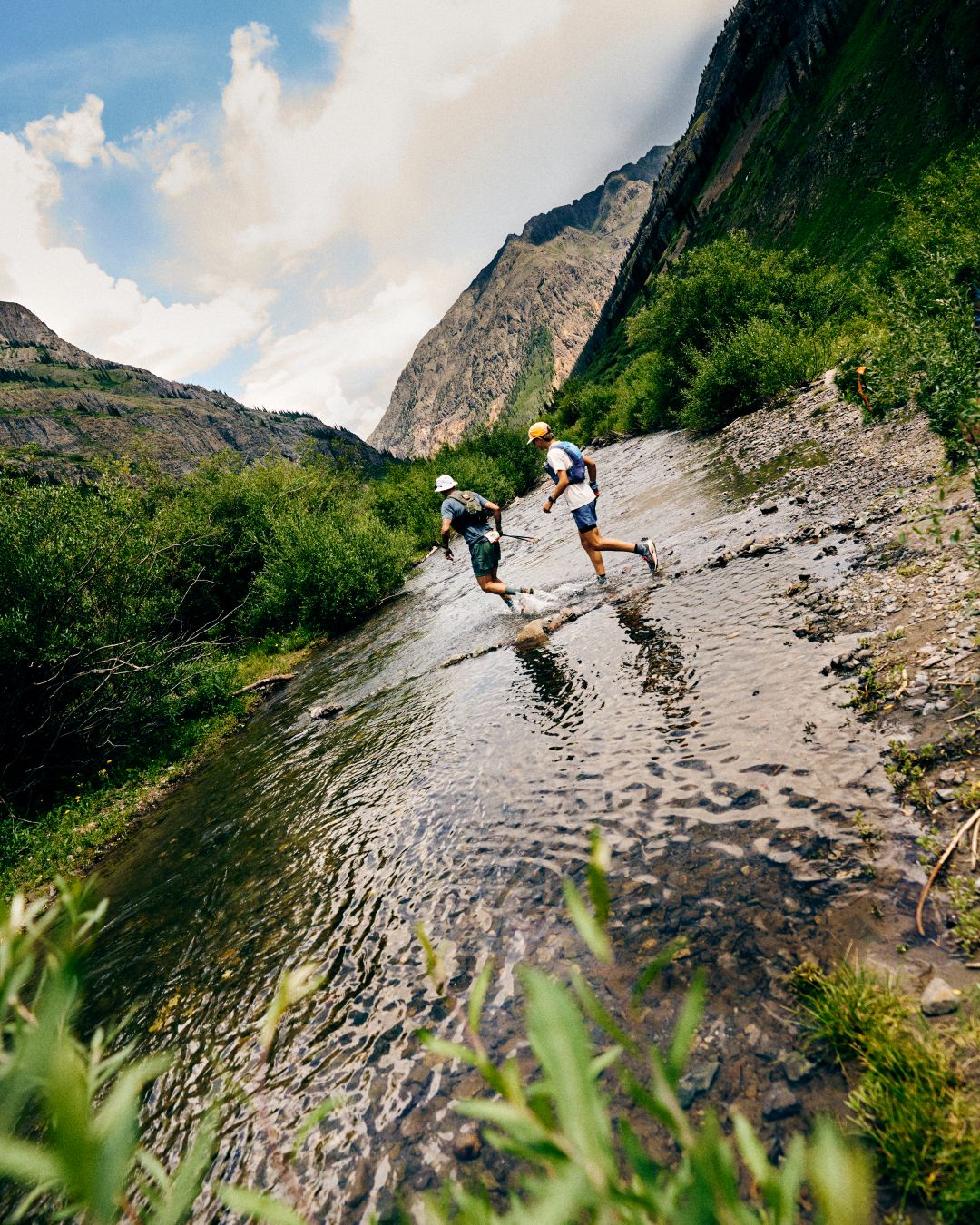 Two runners crossing a stream